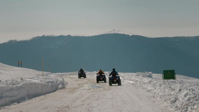 Road with quad bikes on driving down the path in winter. ATVs vechicle on journey to the mountains.