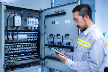 Electrical engineer working check the electric current voltage and overload at front of load center...
