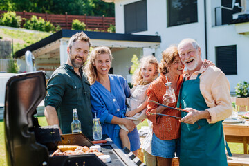 Multi generation family grilling outside on backyard in summer during garden party - obrazy, fototapety, plakaty