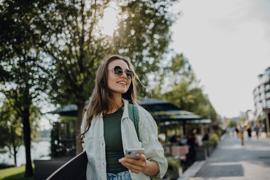 Portrait of young happy woman outdoor with skateboard. Youth culture and commuting concept.