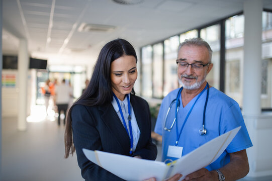 Doctor and business woman in hospital reading documents.