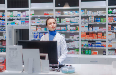 Portrait of young pharmacist selling medication in pharmacy.