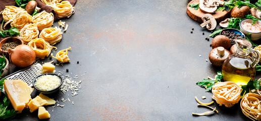 Food background. Uncooked pasta, brown mushrooms, vegetables, cheese and ingredients for tasty cooking on brown table background, top view. Copy space banner