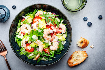 Strawberry, shrimp and herbs healthy salad with arugula, avocado and almond slices, gray kitchen table. Fresh useful dish for healthy eating