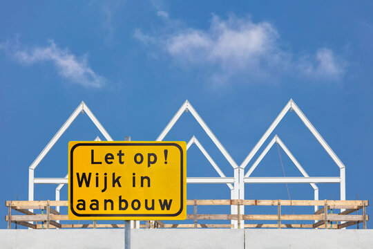 Sign with the Dutch text for "Attention - Residential area under construction" in front of new family homes in The Netherlands