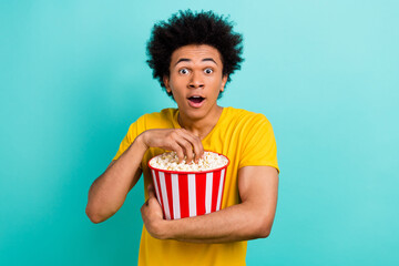 Portrait of impressed handsome man open mouth hold eat popcorn isolated on teal color background