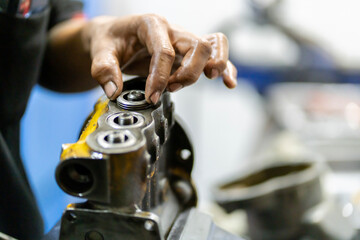 Close-up photos of assembling engine parts or machines that have components that are springs by skilled technicians.