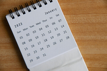 Top view of January 2023 table calendar on wooden cover background