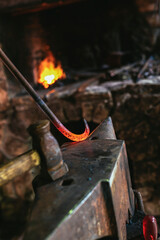 Blacksmith manually forging the molten metal on the anvil in smithy with spark fireworks, close up