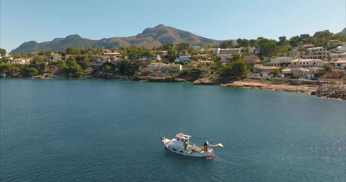 Barco con pescador pescando con casas de fondo, mediterr&aacute;neo (Dji Mavic 3 cine)