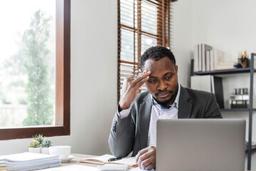 Stressed business man sitting at office workplace. Tired and overworked black man. Young african...