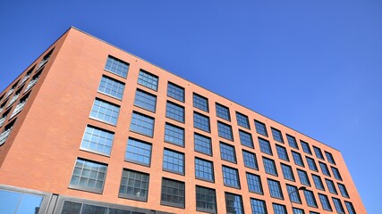 A modern corporate building in the city.  The blue sky is reflected in the buildings large glass windows. Glass facade.