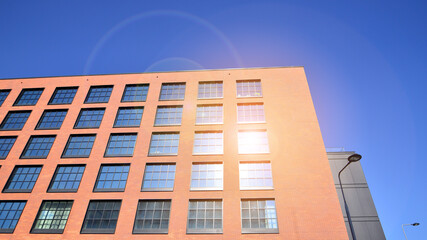 A modern corporate building in the city.  The blue sky is reflected in the buildings large glass windows. Glass facade.