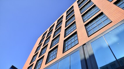Obraz premium A modern corporate building in the city. The blue sky is reflected in the buildings large glass windows. Glass facade.