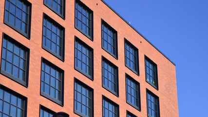A modern corporate building in the city.  The blue sky is reflected in the buildings large glass windows. Glass facade.