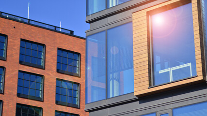 A modern corporate building in the city.  The blue sky is reflected in the buildings large glass windows. Glass facade.