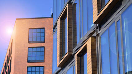 A modern corporate building in the city.  The blue sky is reflected in the buildings large glass windows. Glass facade.