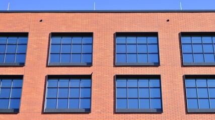 A modern corporate building in the city.  The blue sky is reflected in the buildings large glass windows. Glass facade.