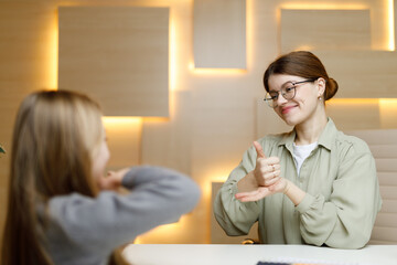 The teacher woman communicates with the child in sign language, training for the deaf.