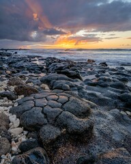 Obraz premium Vertical shot of sunrise over the rocky beach in Oahu, Hawaii.