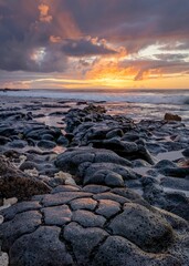 Vertical shot of sunrise over the rocky beach in Oahu, Hawaii.