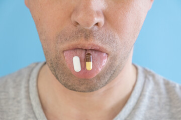 Antiphlogistic white pill and drug for protect stomach medicine capsule on man tongue. Funny shot