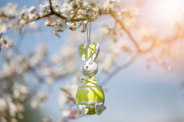 Blooming cherry twigs in the garden, decorated with Easter eggs against blue sky