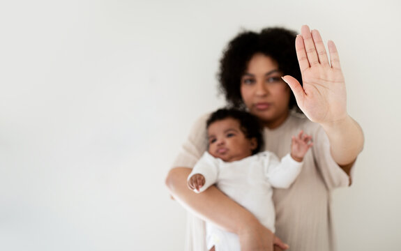 Serious confident young african american lady hold baby in arms, making stop gesture with hand