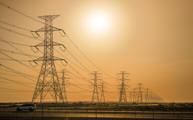 Large tall steel power pylons in rather flat landscape of Saudi Arabia, only black silhouettes...