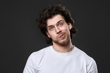 skeptic and nervous man in white t-shirt on dark gray background