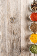 Colourful spices in bowls on wooden table with copyspace. Big collection of spices. Top view