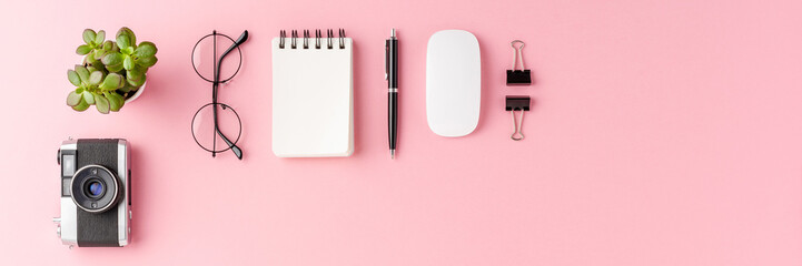 Overhead shot of modern office desktop with business accessories on pink background with copyspace....