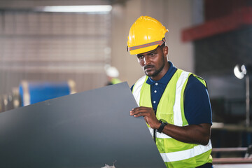 Confident african american man engineer industry worker waering safety hard hat working in factory, Profession technician engineering work in manufacturing warehouse.