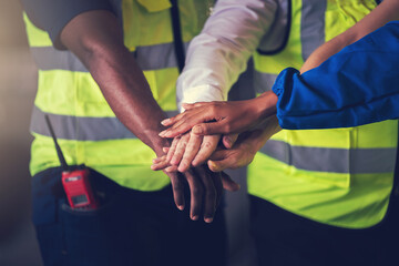 Warehouse worker joint hand together to making teamwork, Cooperation in factory with engineers and technician stacking hands to work together on big industrial project.