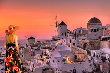 Fototapeta premium A woman looking the sunset of Oia in Santorini, Greece