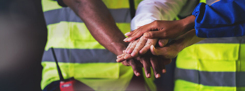 Warehouse worker joint hand together to making teamwork, Cooperation in factory with engineers and technician stacking hands to work together on big industrial project.