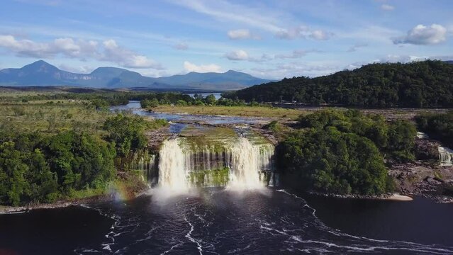 Drone shot over a waterfall with meadows in Parque Nacional Canaima, Venezuela with blue sky