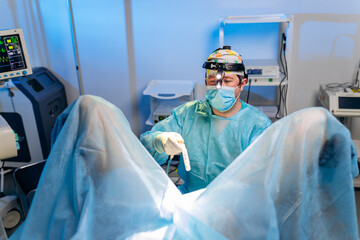 Professional male surgeon proctologist performing operation using special medical devices in the...