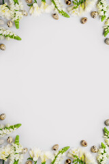Happy Easter holiday mockup. Natural white flowers, green branches and quail eggs on light grey background. Blooming season eco concept. Spring composition layout. Top view, copy space, flat lay.