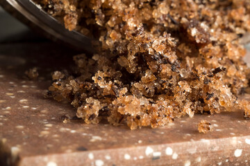 body scrub with sea salt, scattered on a dark surface