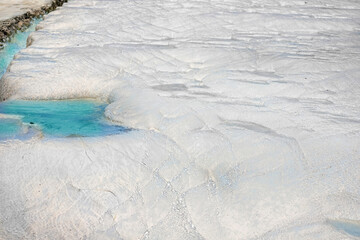 View of natural terraces in Pamukkale on a summer day. Close-up texture of limestone and water flowing over it.