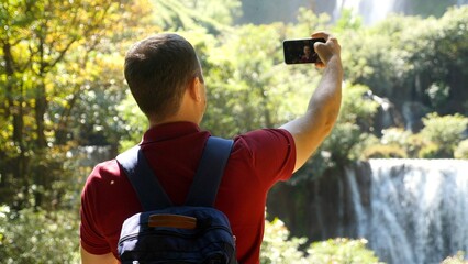 Modern social media content maker, influencer talk on video, shoot blog on mobile phone outdoors. Adult man blogger and vlogger recording selfie movie on his smartphone at nature, look at camera.