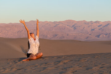 Touristic woman enjoying the sunrise with scenic view on Mesquite Flat Sand Dunes, Death Valley...
