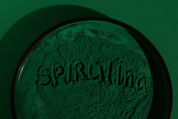 Fresh spirulina algae powder on green background, Spirulina lettering, close-up, organic spirulina...
