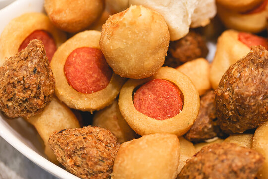Salgados brasileiros variados dentro de uma assadeira branca. Enroladinho de salsicha em destaque. Comida brasileira, lanche, aperitivo, salgadinho.	
