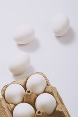 White eggs on bright background and in brown egg tray. Selective focus. Concept scene.