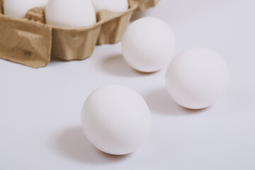 White eggs on bright background and in brown egg tray. Selective focus. Concept scene.