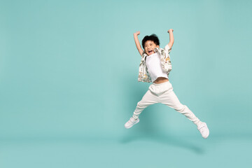Fototapeta na wymiar Asian little boy in flower pattern summer outfits jumping isolated on green background, Five years old