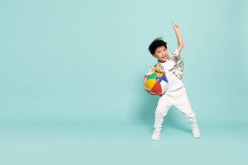 Fototapeta na wymiar Asian little boy in flower pattern summer outfits holding beach ball isolated on green background, Five years old