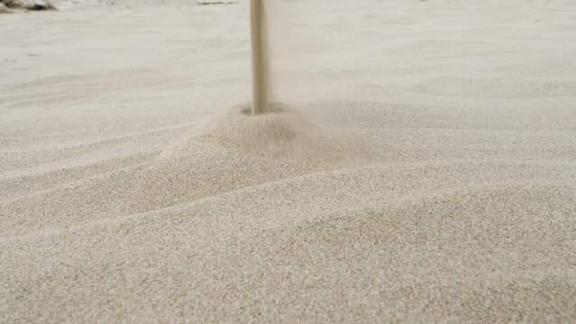 Stream of sand falling. White sand forms a pile on the beach